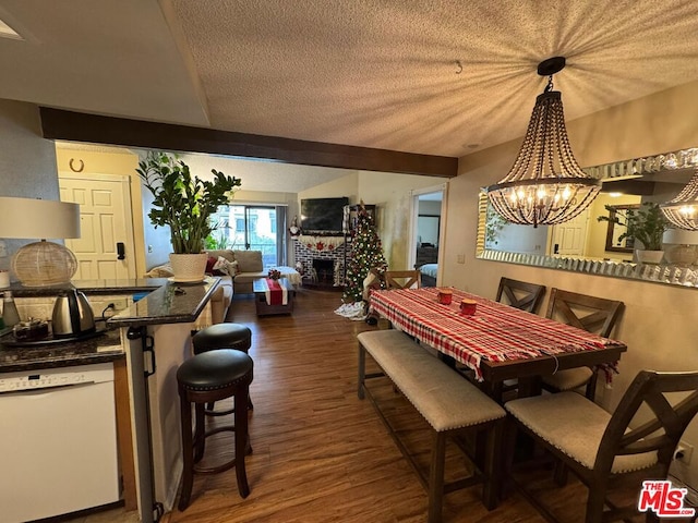 dining area with a brick fireplace, dark hardwood / wood-style flooring, a textured ceiling, and an inviting chandelier