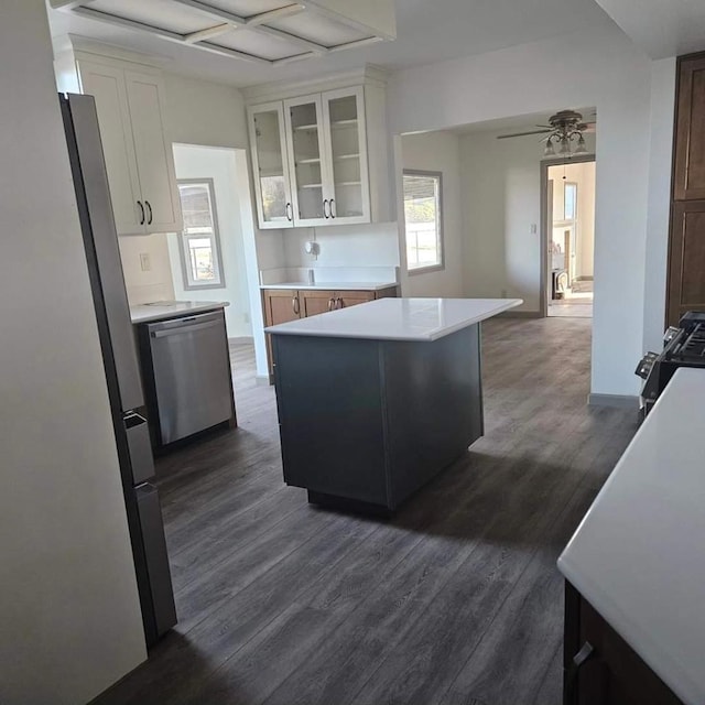 kitchen with appliances with stainless steel finishes, a kitchen island, white cabinetry, dark hardwood / wood-style flooring, and ceiling fan