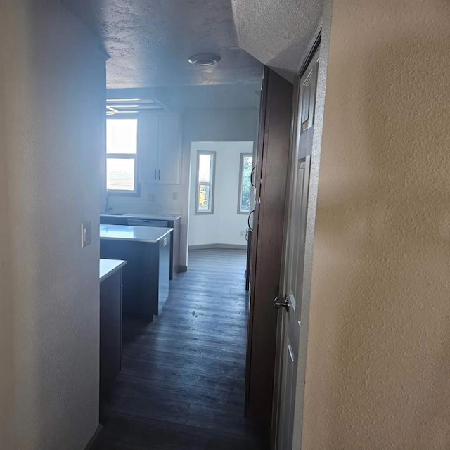 hall featuring a textured ceiling and dark hardwood / wood-style floors