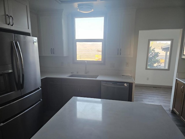 kitchen featuring appliances with stainless steel finishes, sink, white cabinetry, and dark hardwood / wood-style floors