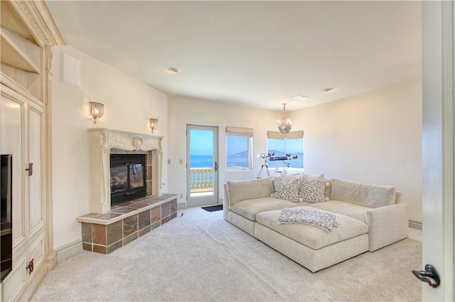 living area with a tile fireplace, a notable chandelier, baseboards, and carpet floors
