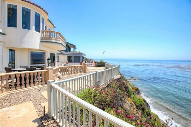 exterior space featuring a patio, a water view, area for grilling, and a beach view