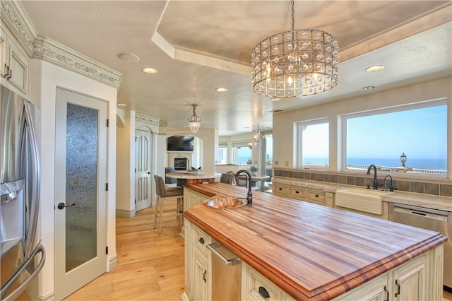 kitchen with light wood-type flooring, a center island, sink, stainless steel appliances, and decorative light fixtures