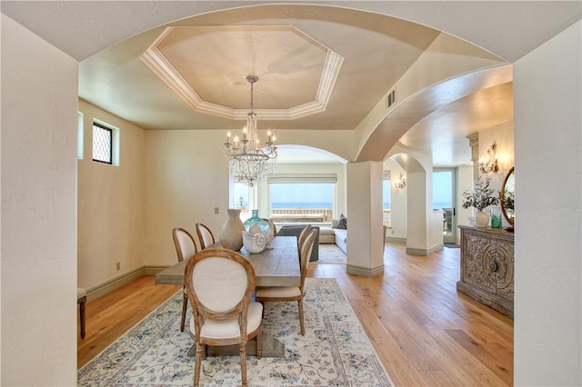 dining room with arched walkways, a notable chandelier, visible vents, and light wood-type flooring