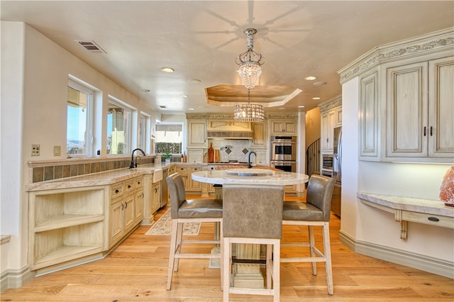 kitchen featuring light hardwood / wood-style floors, a kitchen bar, pendant lighting, and stainless steel appliances