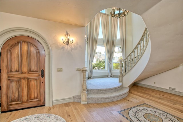 foyer featuring light wood-style floors, an inviting chandelier, baseboards, and stairway