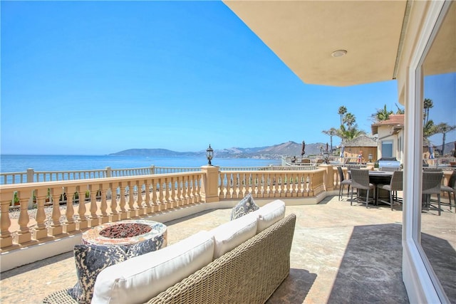 view of patio featuring an outdoor living space with a fire pit, outdoor dining space, and a water and mountain view