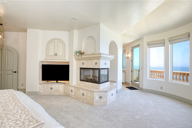 bedroom with access to outside, baseboards, a tiled fireplace, and light colored carpet