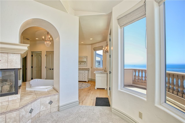 bathroom with vanity, hardwood / wood-style flooring, a notable chandelier, tiled bath, and a water view