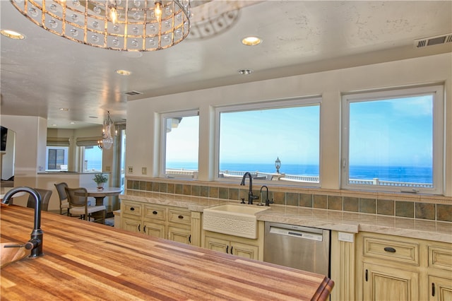 kitchen with a notable chandelier, a water view, dishwasher, and sink