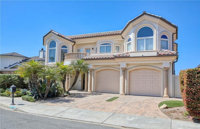 mediterranean / spanish house with a tiled roof, a garage, and stucco siding