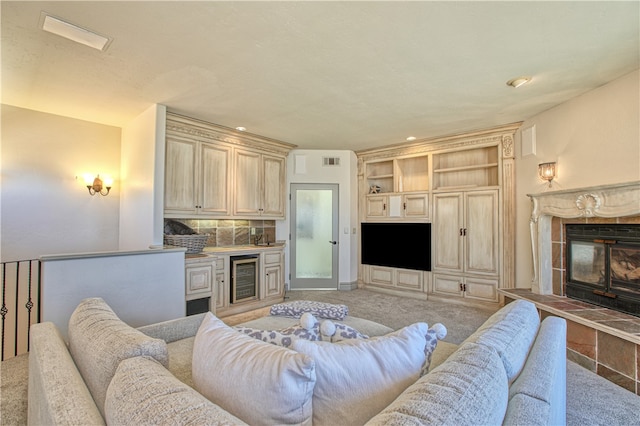 carpeted living room featuring built in shelves, a tiled fireplace, and wine cooler