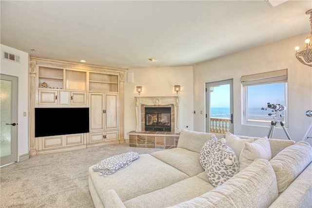 living room featuring a fireplace, carpet flooring, visible vents, and a notable chandelier