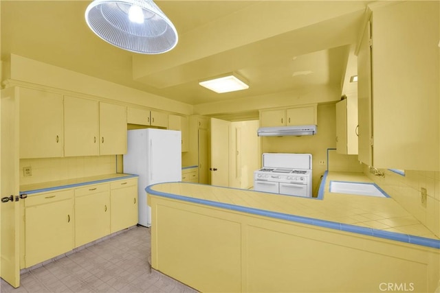 kitchen with tile countertops, decorative backsplash, white appliances, and kitchen peninsula