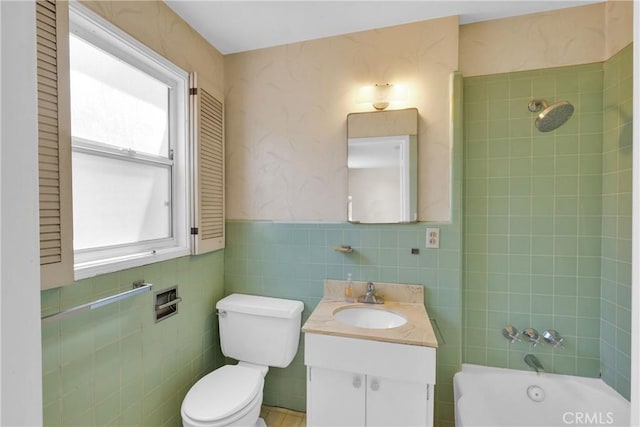 full bathroom featuring vanity, tiled shower / bath combo, tile walls, and toilet