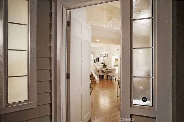 hall with a notable chandelier and hardwood / wood-style flooring