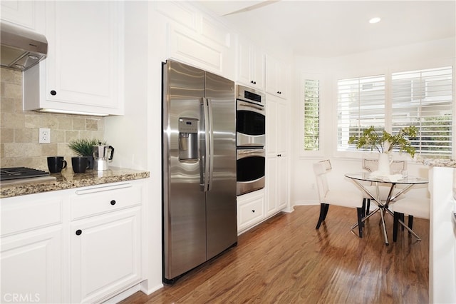 kitchen featuring stone countertops, white cabinetry, exhaust hood, stainless steel appliances, and dark hardwood / wood-style flooring