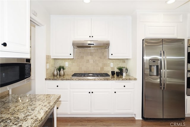 kitchen featuring appliances with stainless steel finishes, white cabinetry, light stone counters, backsplash, and dark hardwood / wood-style flooring