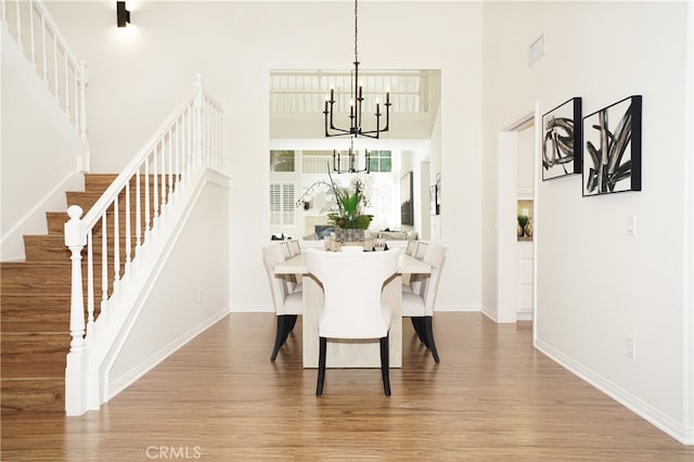 dining room with a notable chandelier, hardwood / wood-style floors, and a high ceiling