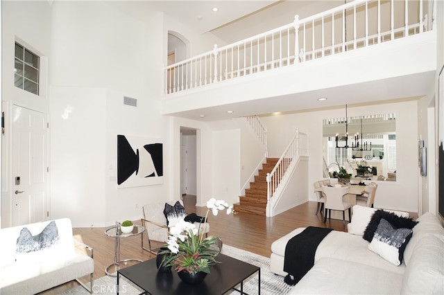 living room featuring a high ceiling, a chandelier, and wood-type flooring