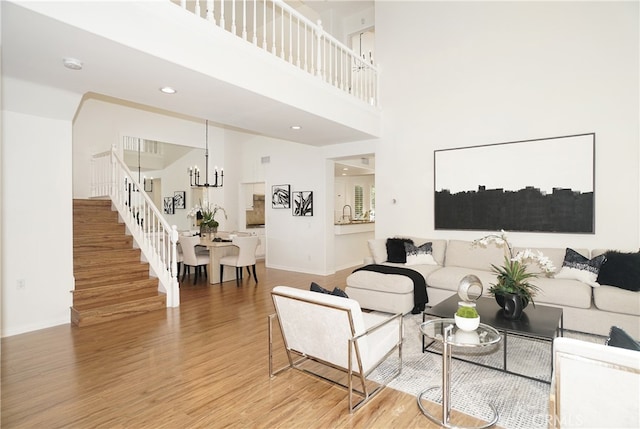 living room with hardwood / wood-style flooring, a chandelier, and a high ceiling