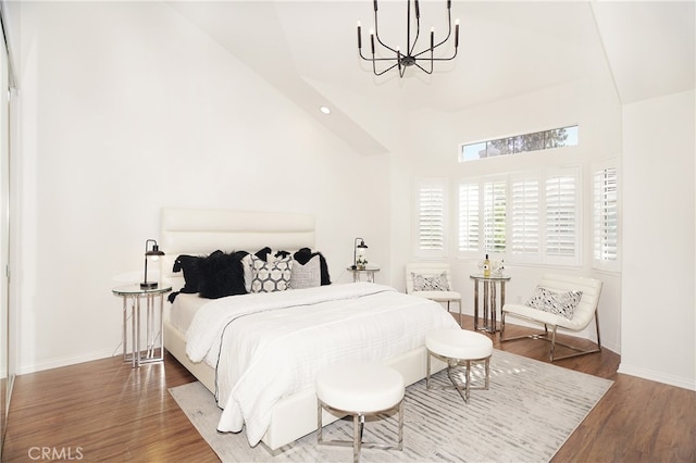 bedroom with high vaulted ceiling, a notable chandelier, and hardwood / wood-style floors