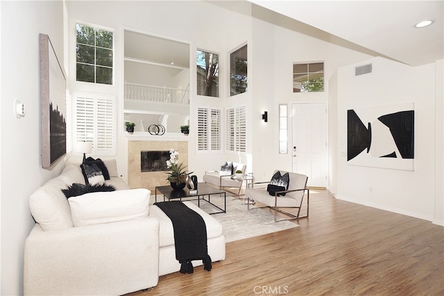 living room featuring a tile fireplace, hardwood / wood-style floors, and a high ceiling