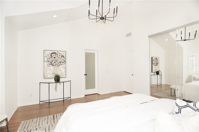 bedroom with an inviting chandelier, a high ceiling, and hardwood / wood-style floors