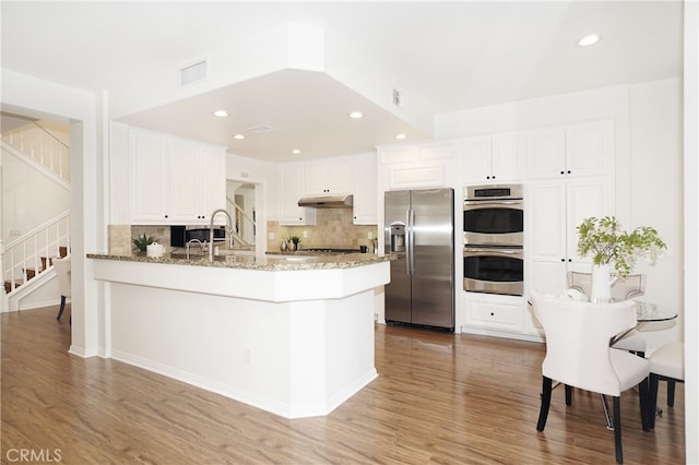 kitchen with stainless steel appliances, hardwood / wood-style floors, and white cabinetry