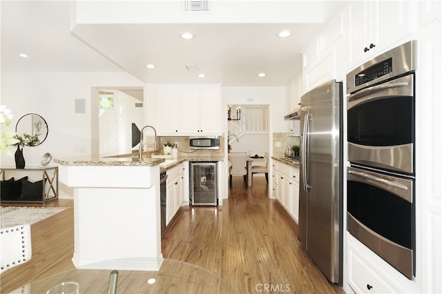 kitchen with appliances with stainless steel finishes, beverage cooler, and white cabinets