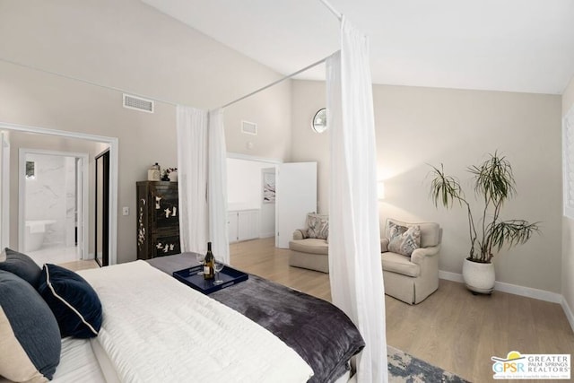 bedroom with light wood-type flooring, connected bathroom, and vaulted ceiling