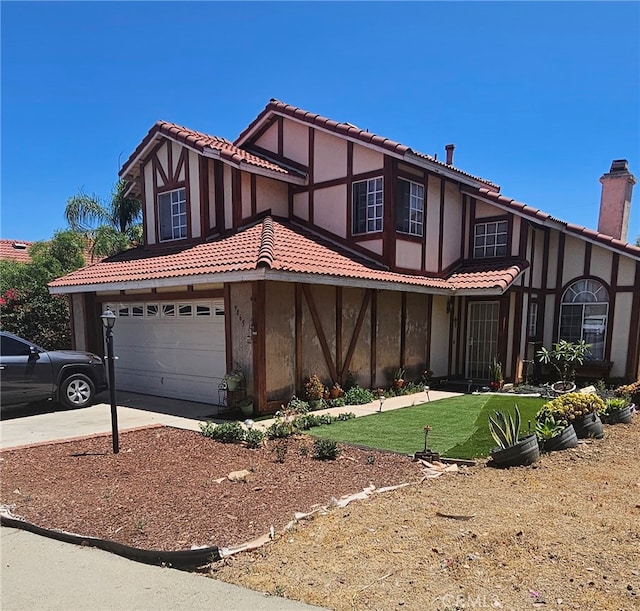 tudor home featuring a front yard and a garage