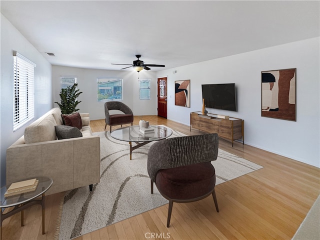 living room with visible vents, light wood-style flooring, and a ceiling fan