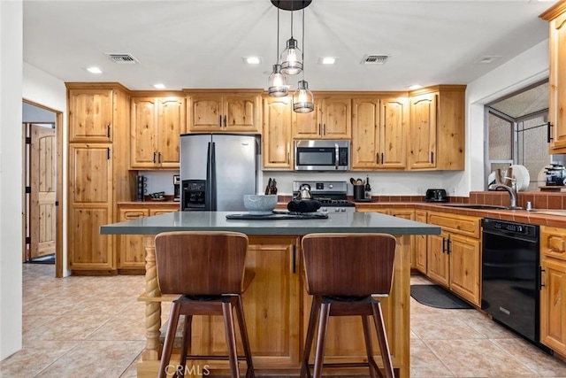 kitchen with light tile patterned flooring, appliances with stainless steel finishes, sink, and a kitchen island