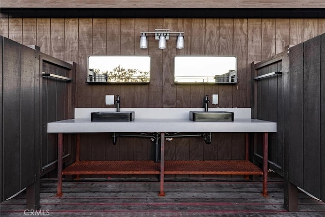 bathroom with hardwood / wood-style floors, dual sinks, and wooden walls