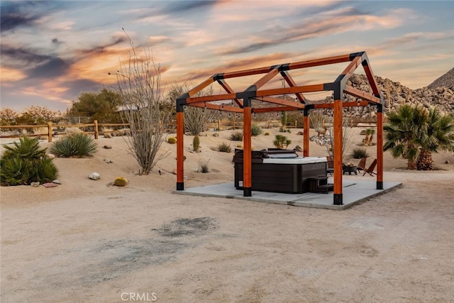 patio terrace at dusk featuring a hot tub