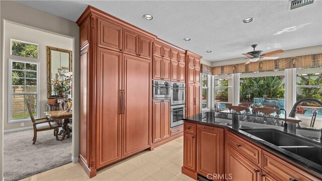 kitchen featuring dark stone counters, light colored carpet, and a healthy amount of sunlight