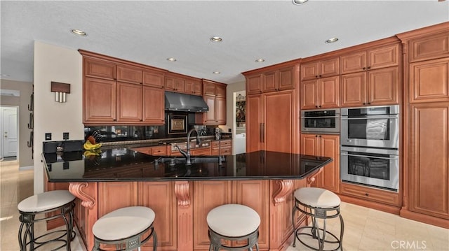 kitchen featuring sink, double oven, kitchen peninsula, decorative backsplash, and a breakfast bar