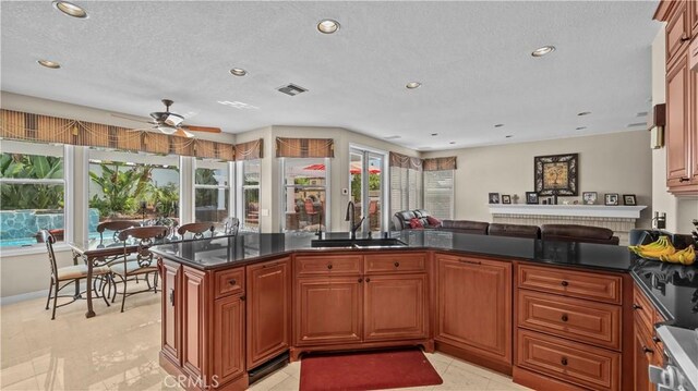 kitchen with kitchen peninsula, ceiling fan, sink, and a textured ceiling