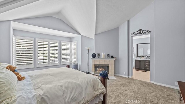 carpeted bedroom with a tile fireplace, connected bathroom, and vaulted ceiling