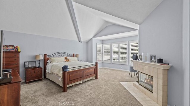 carpeted bedroom featuring vaulted ceiling with beams and a tiled fireplace