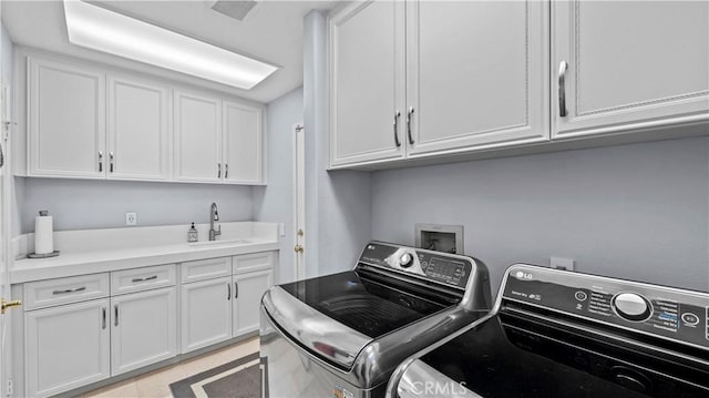 clothes washing area featuring cabinets, washing machine and dryer, and sink