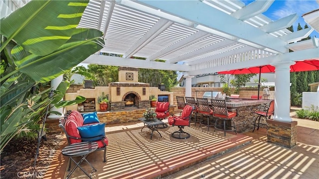 view of patio / terrace with exterior bar, an outdoor stone fireplace, and a pergola