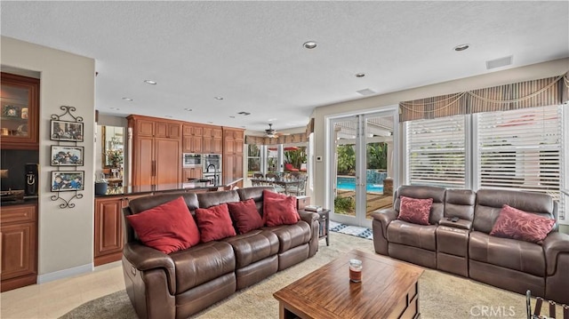 living room with french doors, a textured ceiling, and light tile patterned flooring