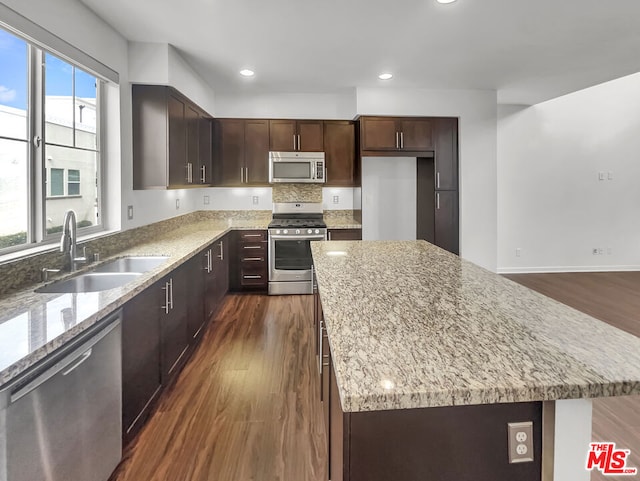 kitchen with dark hardwood / wood-style floors, appliances with stainless steel finishes, plenty of natural light, and a kitchen island