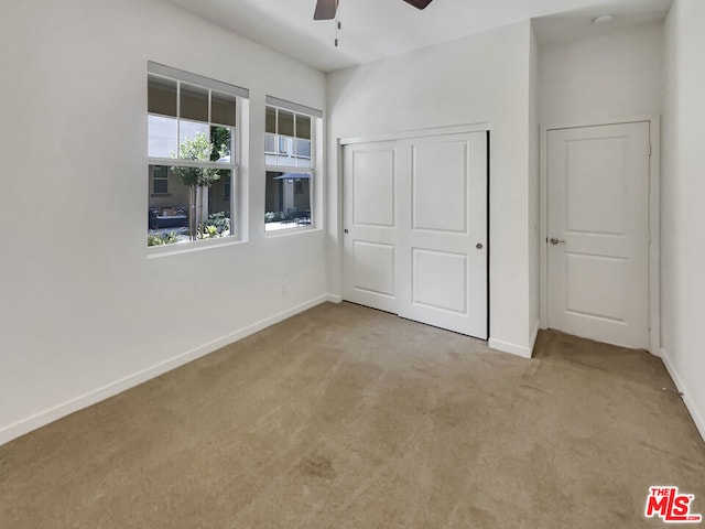 unfurnished bedroom featuring ceiling fan, light colored carpet, and a closet