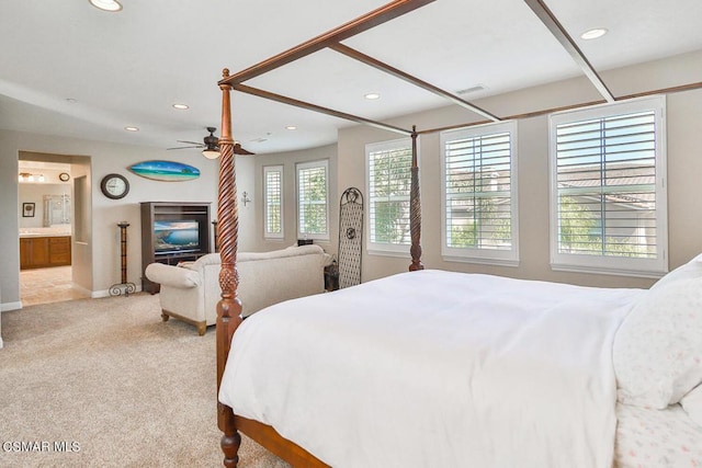 bedroom with ensuite bath, ceiling fan, light carpet, and multiple windows