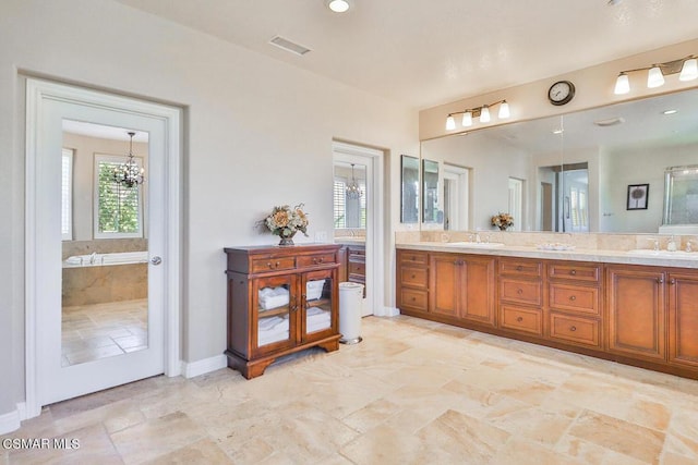 bathroom with a bathing tub, vanity, and an inviting chandelier