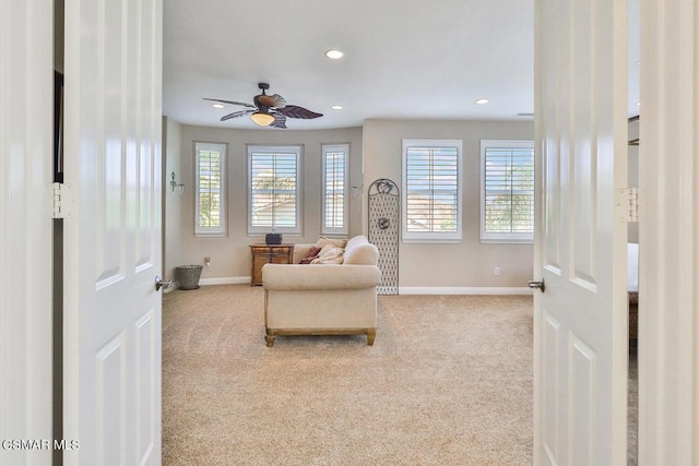 living area with light carpet, plenty of natural light, and ceiling fan