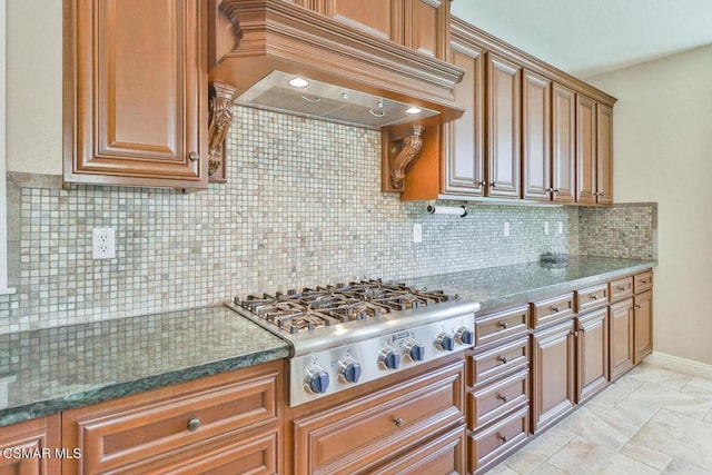 kitchen featuring backsplash, stainless steel gas stovetop, dark stone countertops, and premium range hood